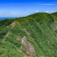 初夏の浅草岳稜線を歩む登山者と新緑の登山道の写真