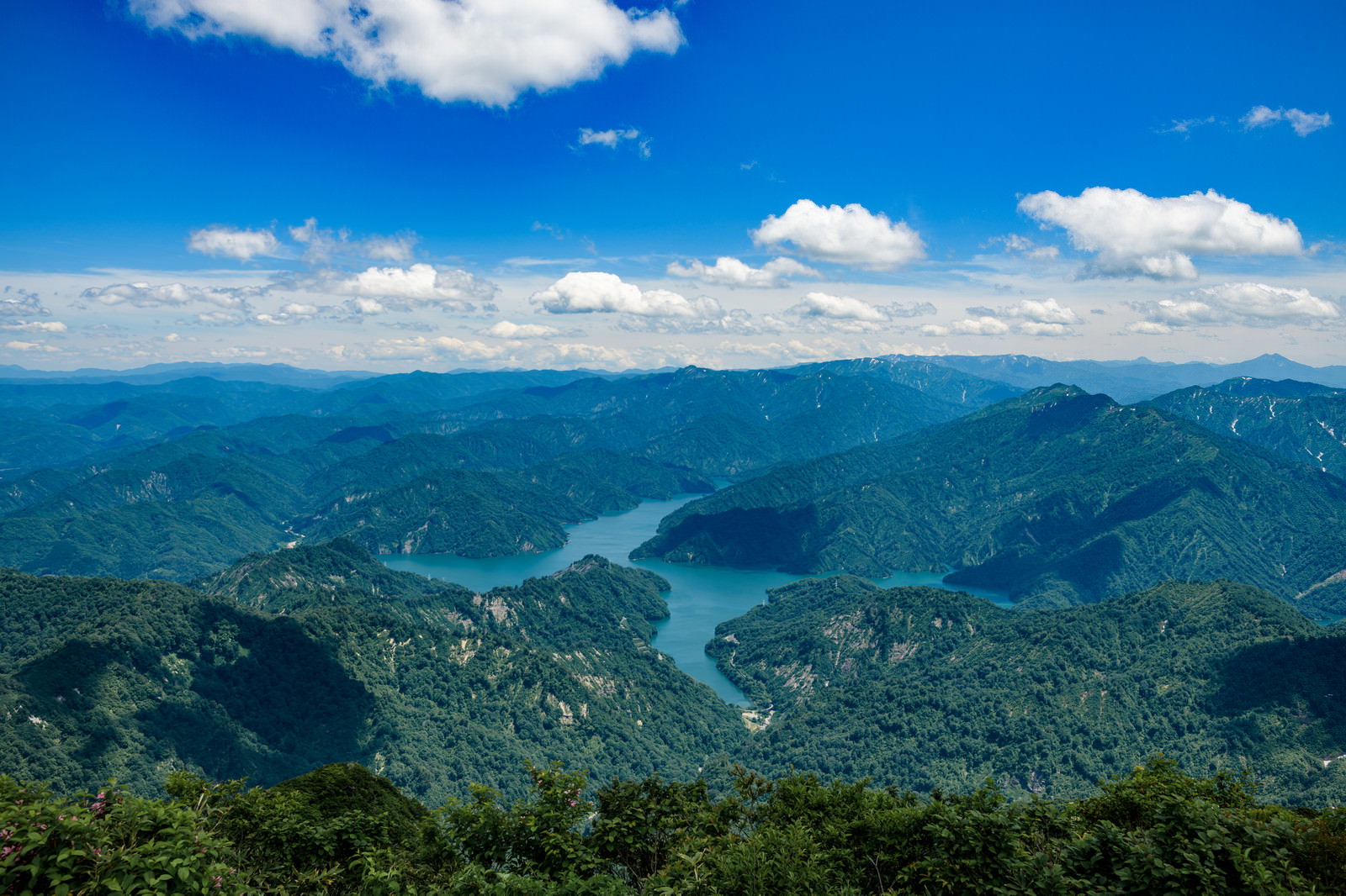 福島県の浅草岳から見た守門岳と青い田子倉湖、緑の山々が連なる山岳風景