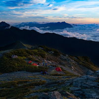 南アルプスの夜明けと雲海を望む登山者の写真