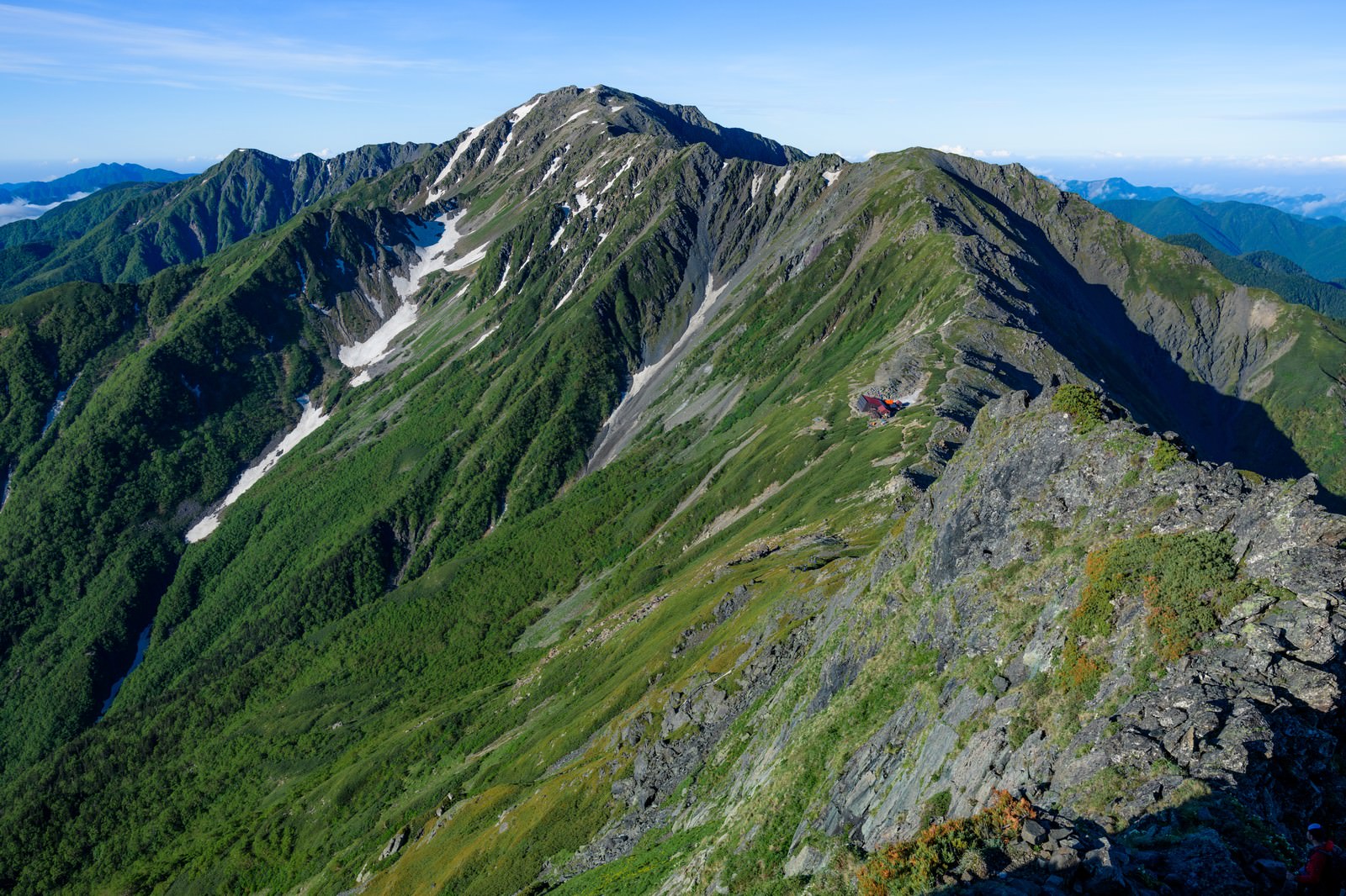 北岳から見た間ノ岳への稜線、緑の山肌と青空が広がる南アルプスの山並み