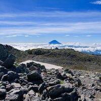 南アルプス間ノ岳の山頂から雲海に浮かぶ富士山を望むの写真