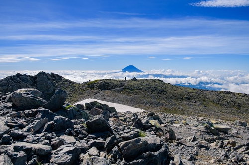 南アルプス間ノ岳の山頂から雲海に浮かぶ富士山を望む