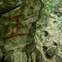 登山道の岩壁に描かれた赤い正の字の目印と道しるべの写真