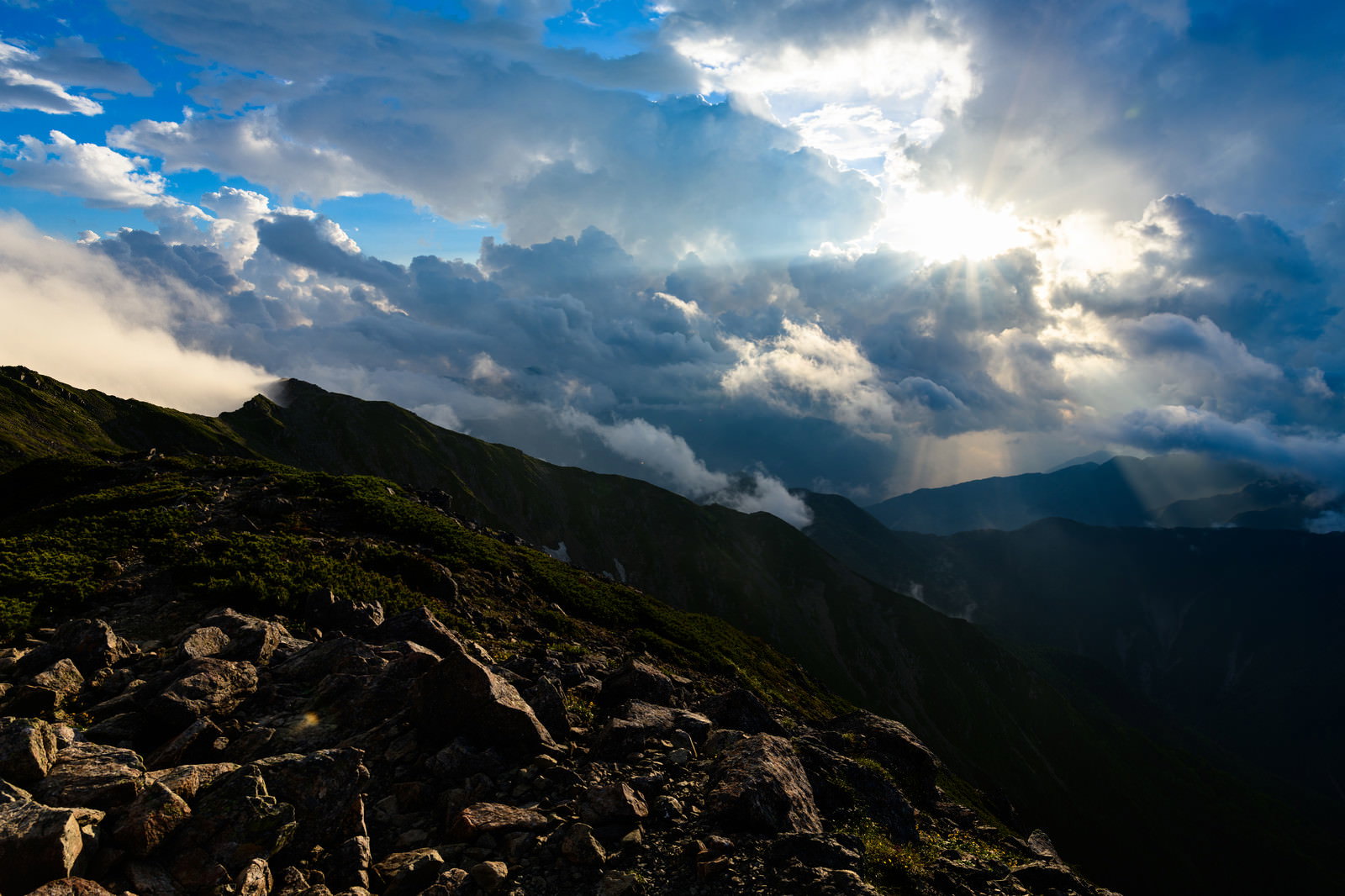 中岳避難小屋から見える夕日の光芒が雲間から山々に差し込む風景
