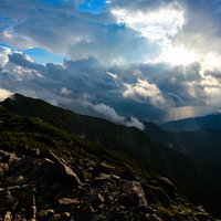 中岳避難小屋から見る夕日の光芒が山々を照らす光景の写真