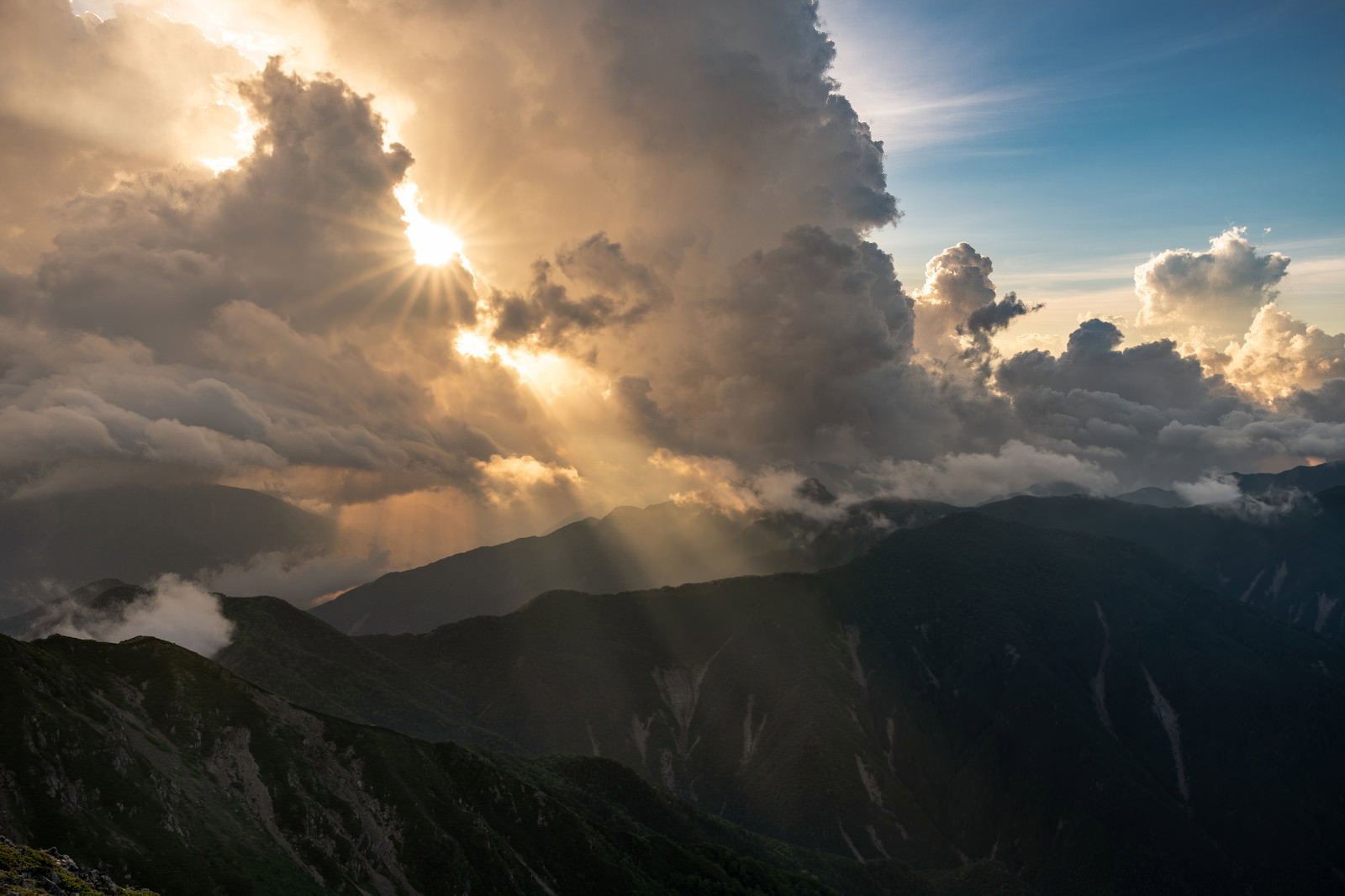 南アルプスの山々に雲の合間から薄明光線が降り注ぐ風景