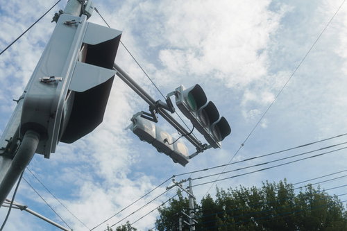 歩道から見上げる信号機と青空