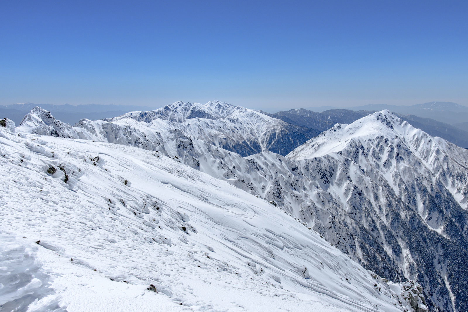 雪に覆われた三ノ沢岳と空木岳の山々が青空の下に連なる冬山の風景