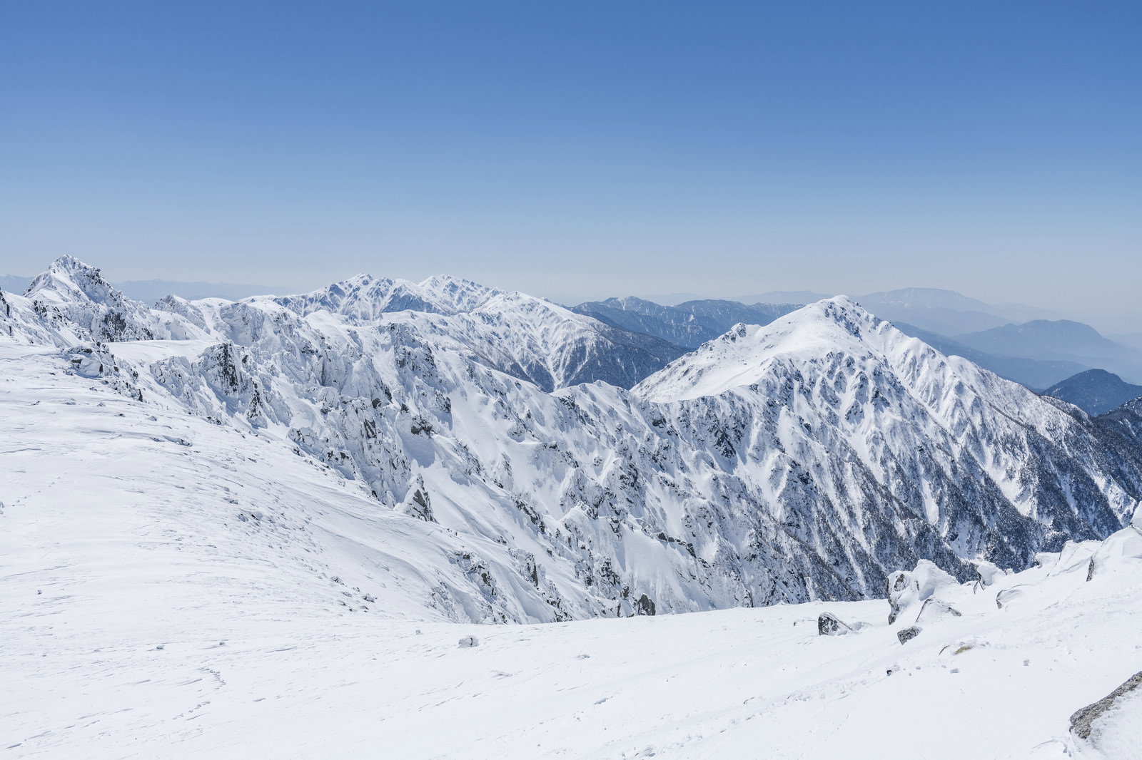 雪化粧した三ノ沢岳方面の山々と青空が広がる冬の登山道からの眺望