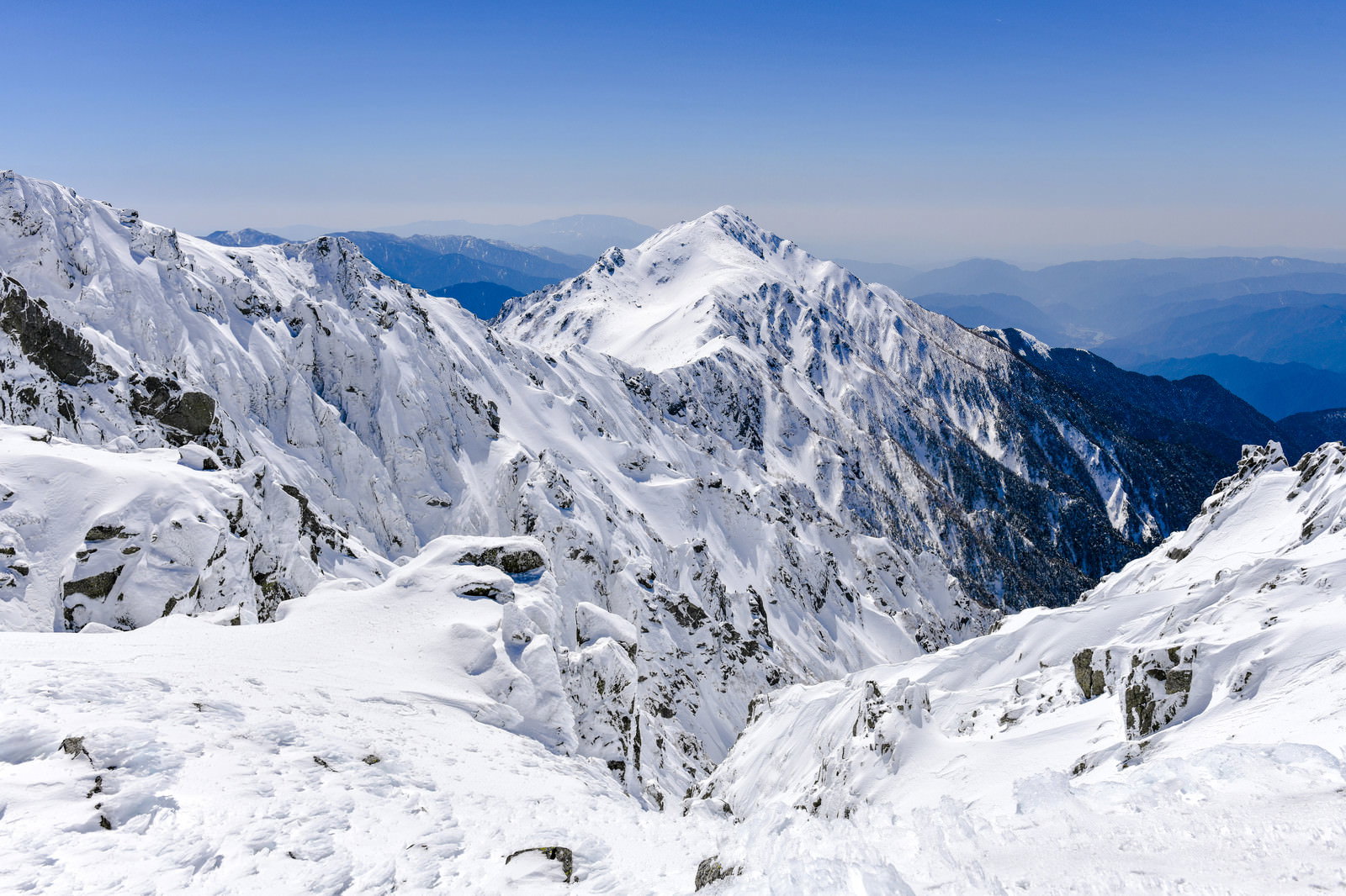 青空をバックに雪化粧した三ノ沢岳の山々が連なる冬の遠景