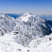 青空と雪化粧した三ノ沢岳の遠景の写真