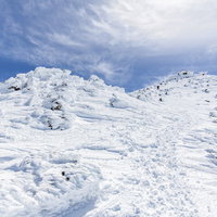 冬の乗鞍岳山頂を望む飛騨山脈の雪景色と青空の写真