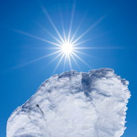 青空に輝く光芒と樹氷に覆われた木々の冬景色の写真