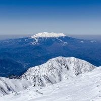 青空に映える冠雪する御嶽山の雪山風景の写真