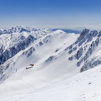 冬の千畳敷カールに建つホテル千畳敷と積雪した山々の稜線の写真