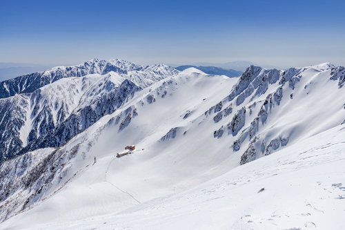 冬の千畳敷カールに建つホテル千畳敷と積雪した山々の稜線