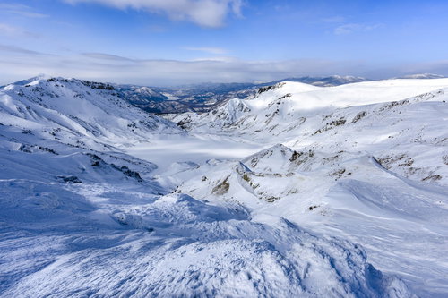 雪に埋もれた安達太良山の爆裂火口と冬の火山地形