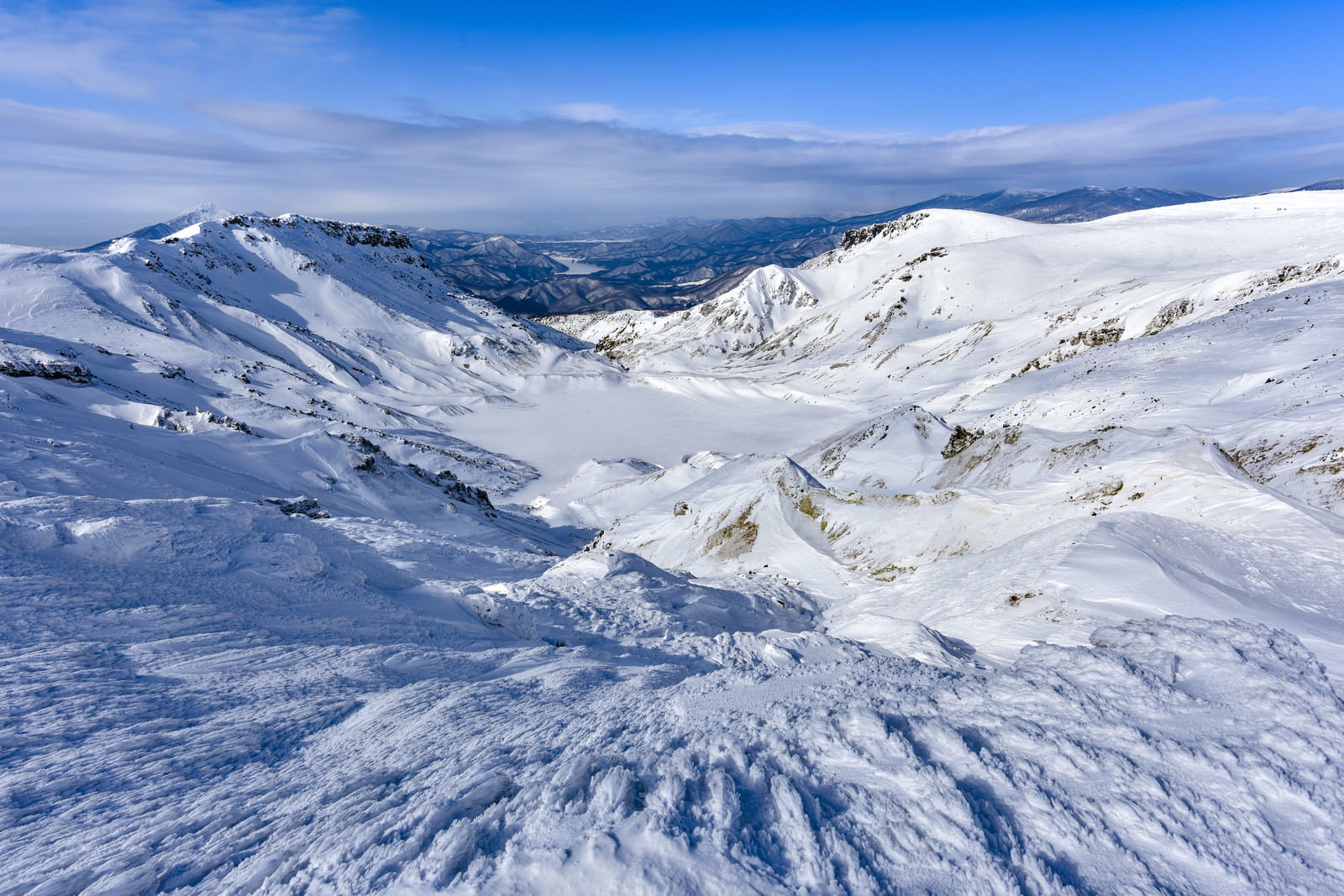 雪に覆われた安達太良山の爆裂火口と青空が広がる冬山の風景