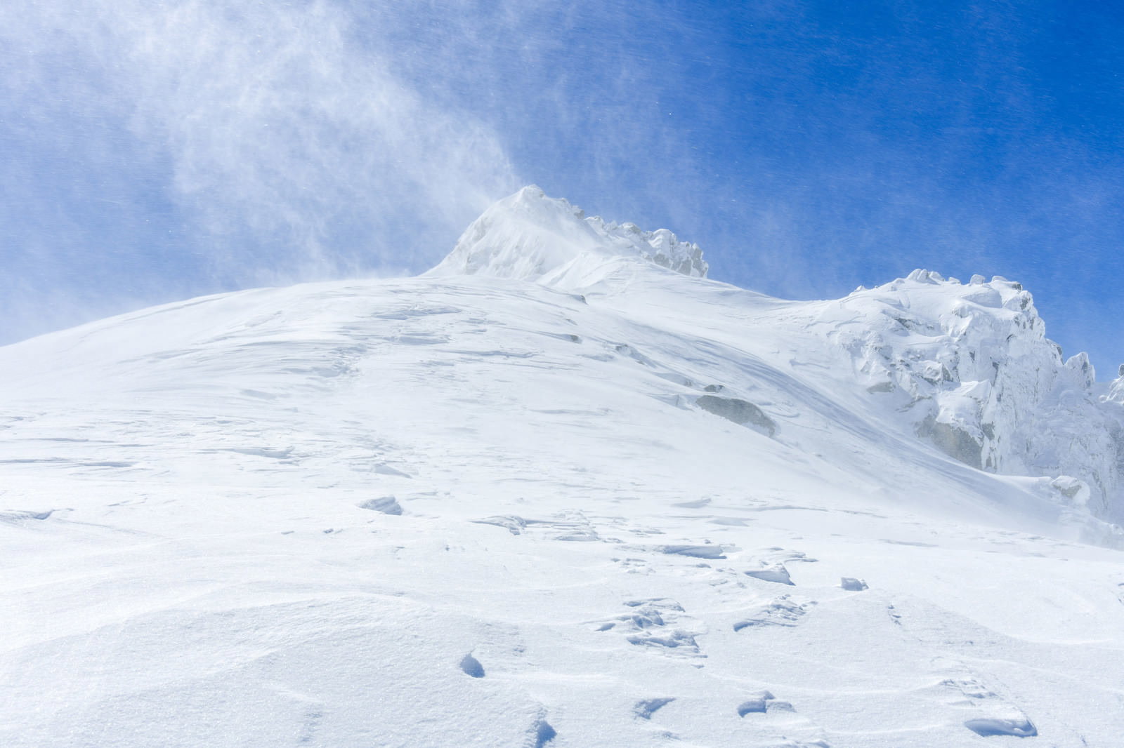 雪化粧した山頂と青空に白い雲が広がる冬の山岳風景