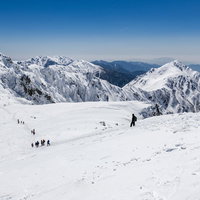 冬の中央アルプスの雪原を歩く登山者たちの風景の写真
