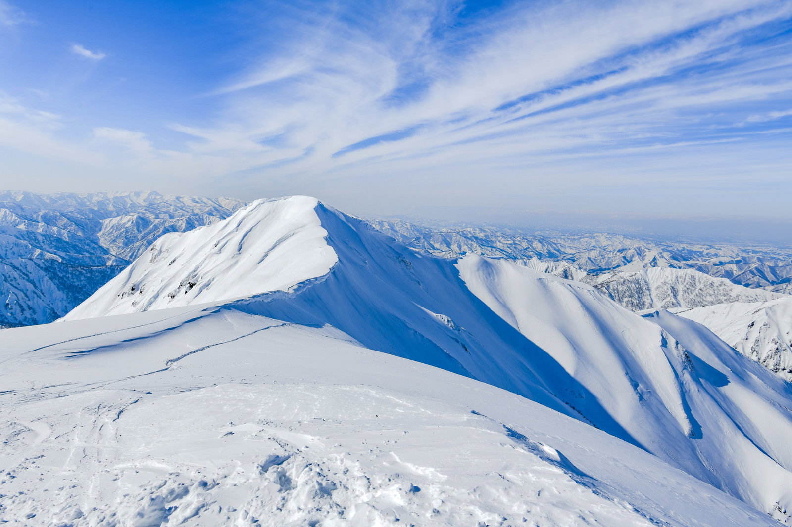 茂倉岳方面の雪に覆われた山稜と青空が広がる冬山の風景