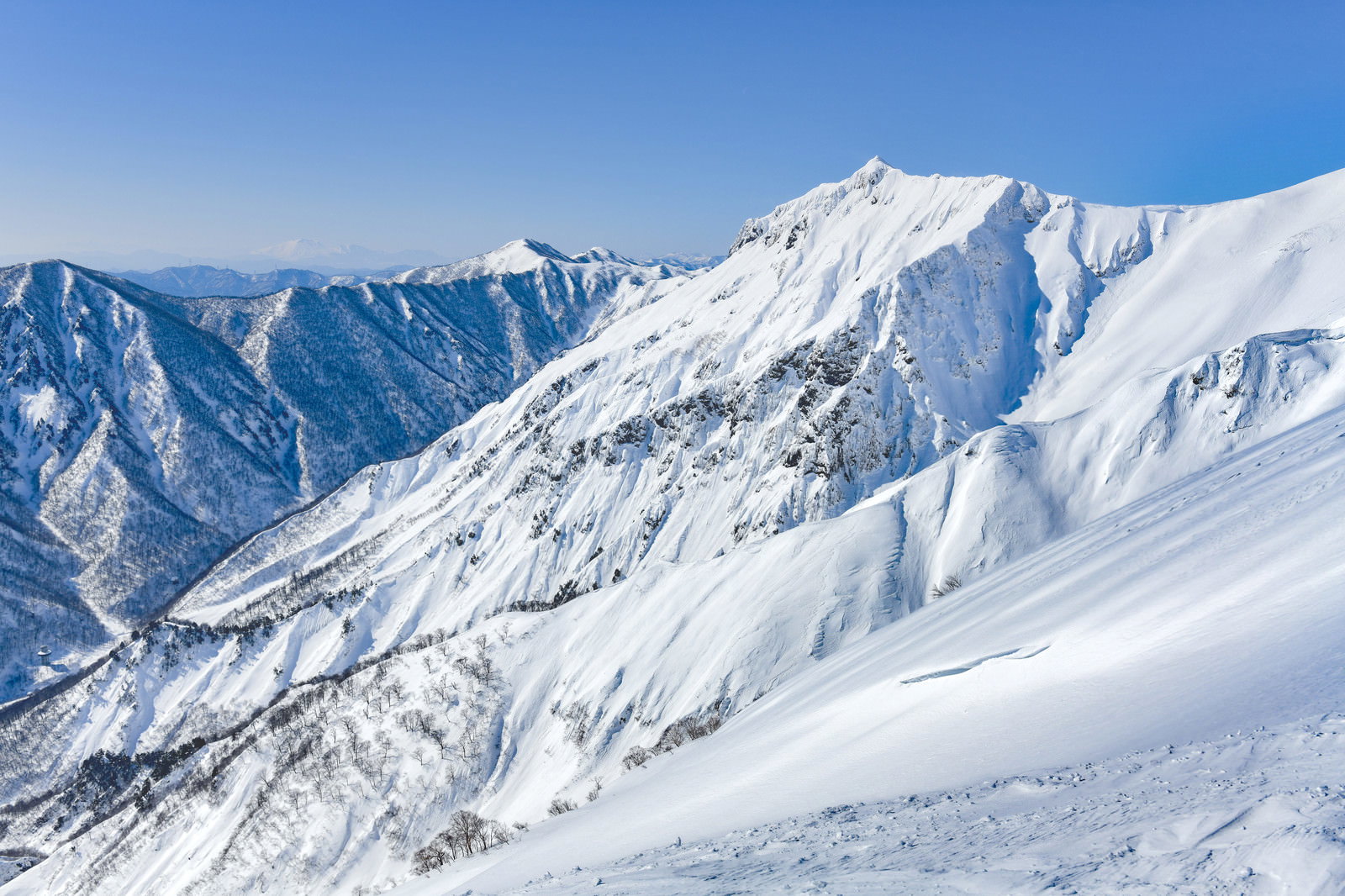 雪に覆われた谷川岳の山々と青空が広がる冬の登山道からの景色