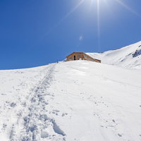 雪原の山小屋への帰り道、深い雪に続く足跡の写真