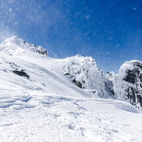 風雪舞う宝剣岳の険しい岩峰（木曽山脈）冬の雪山の写真