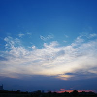 さいたま新都心の向こうへと沈んでいく夕日と雲の青空の写真