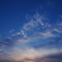 ダイナミックな動きを見せる雲と焼ける地平線の夕焼け空の写真