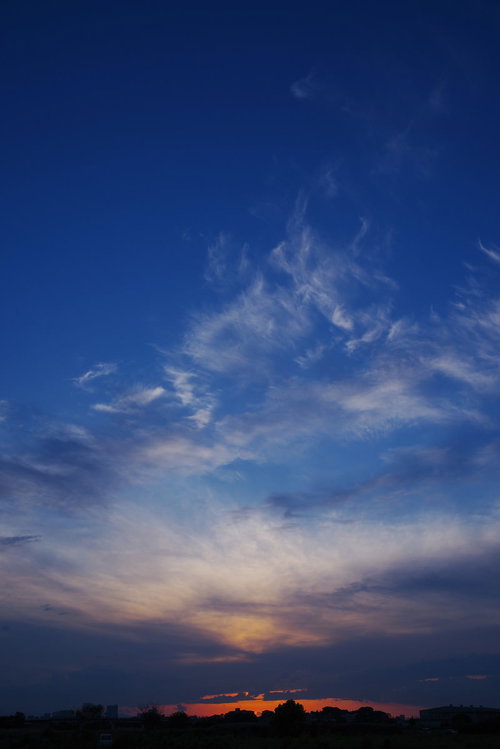ダイナミックな動きを見せる雲と焼ける地平線の夕焼け空