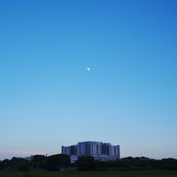 夕暮れ空に浮かぶ月と建物のシルエット、グラデーション空の写真