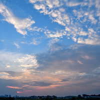 夕日と青空が入り混じる夕焼けの空と地平線の建物シルエットの写真