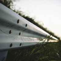 夕暮れへと続く道路のガードレールの写真