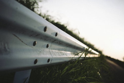 夕暮れへと続く道路のガードレール