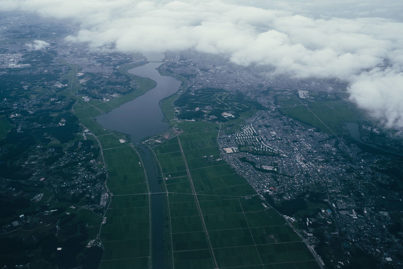 上空から撮影した川沿いの田園地帯と住宅地の風景