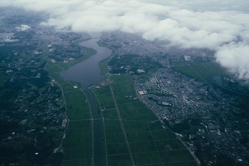 川沿いの田園地帯と整備された街並みを上空から捉えた風景
