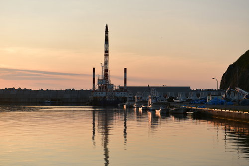 夕暮れの港に停泊する船と波穏やかな水面に映る風景
