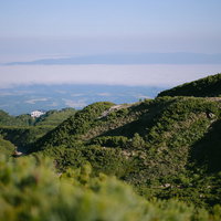 十勝岳中腹から雲海に浮かぶ宿と山肌を見下ろす絶景の写真