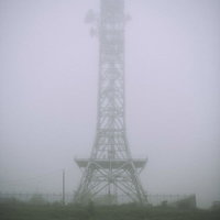 濃い霧の中に立つ送電鉄塔のシルエットの写真