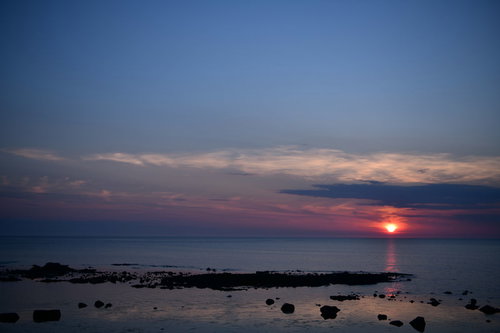 青い海に沈むオレンジ色の太陽の夕日、ピンク色の雲と水平線