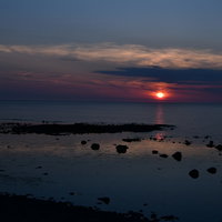 青と赤のコントラストが激しい落日、水平線に沈む夕日の写真