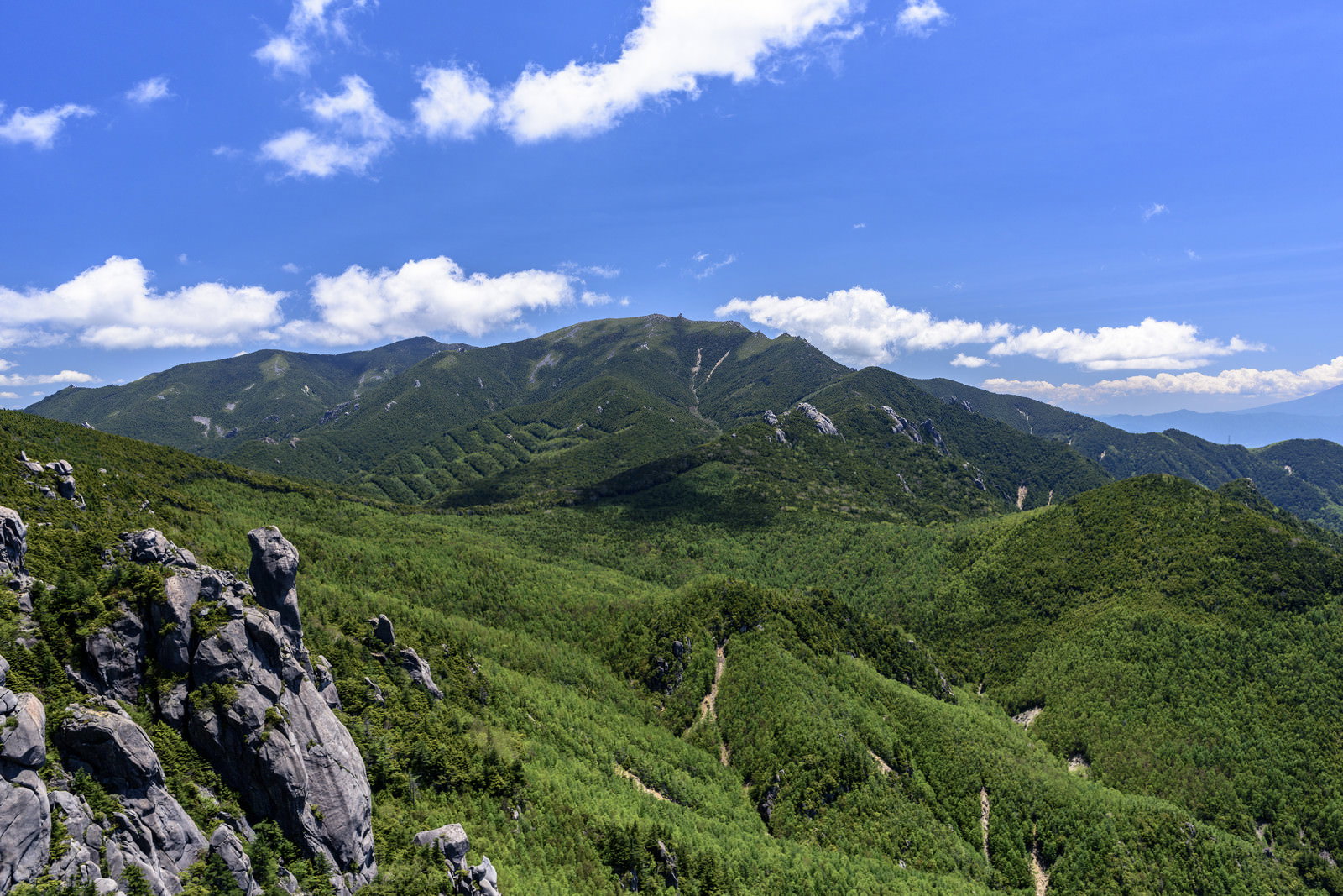 青空の下、瑞牆山から眺める緑の山稜線と金峰山の岩峰