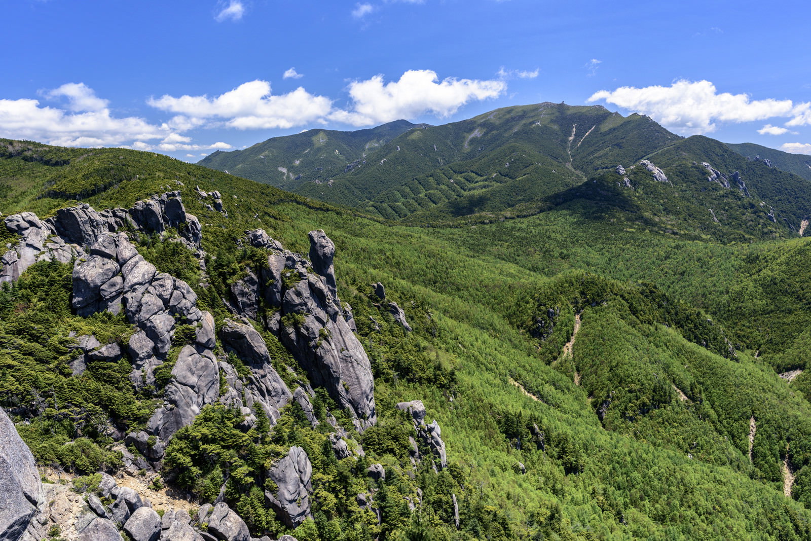 瑞牆山の巨石群と奥に広がる金峰山の山々を青空の下で撮影した風景