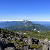 トムラウシ山頂の岩場から十勝岳方面を望む雄大な山並みの写真