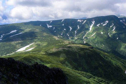 大雪山系の化雲岳、緑の山稜に雲が迫る景観