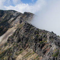 雲が押し寄せる浅間山の外輪山と稜線の火山地形の写真