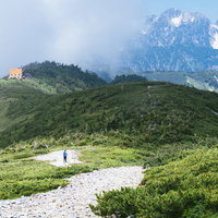 種池山荘へ向かう登山道で剱岳を背に進む登山者の写真