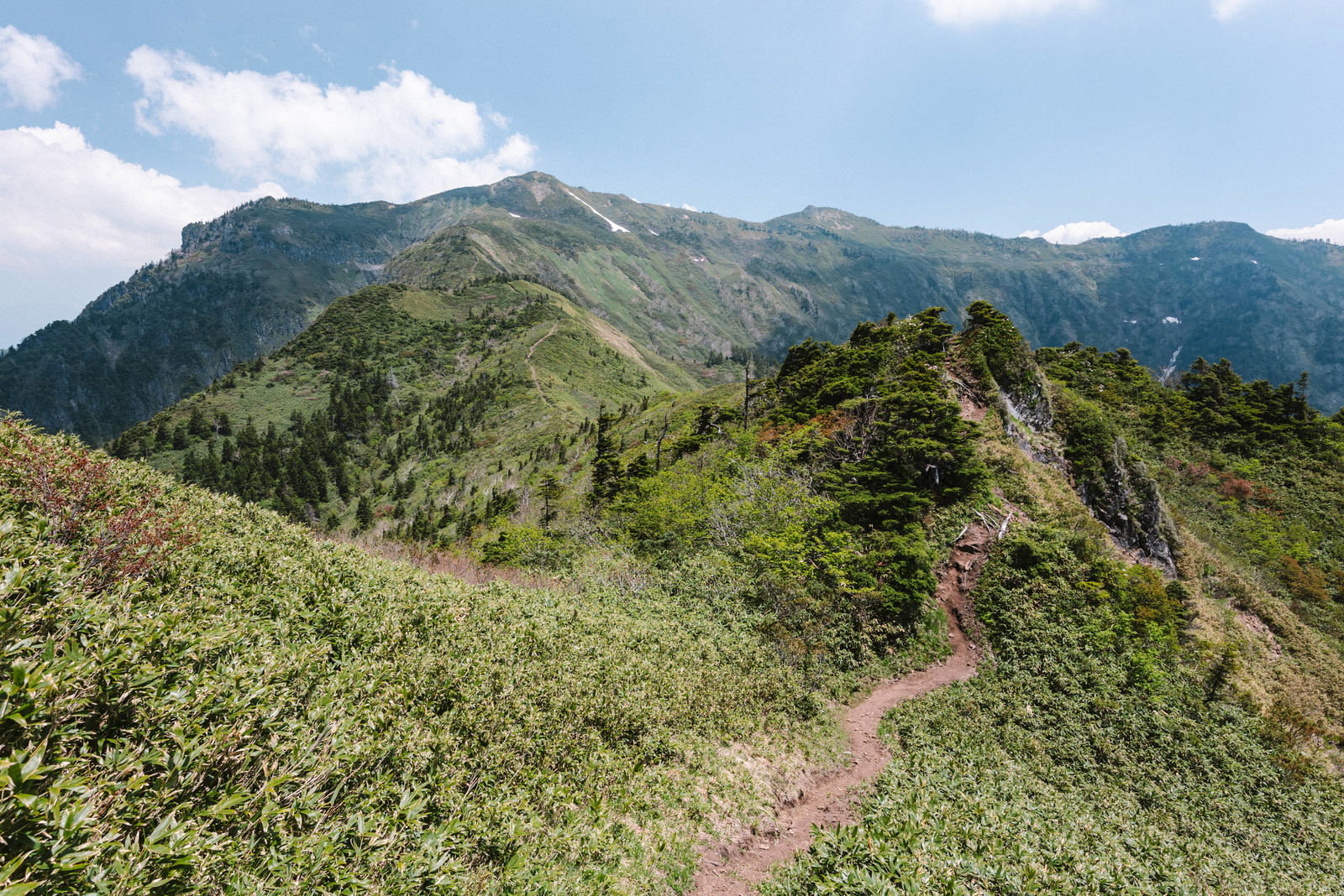 剣ヶ峰から眺める沖武尊の山並みと登山道の風景