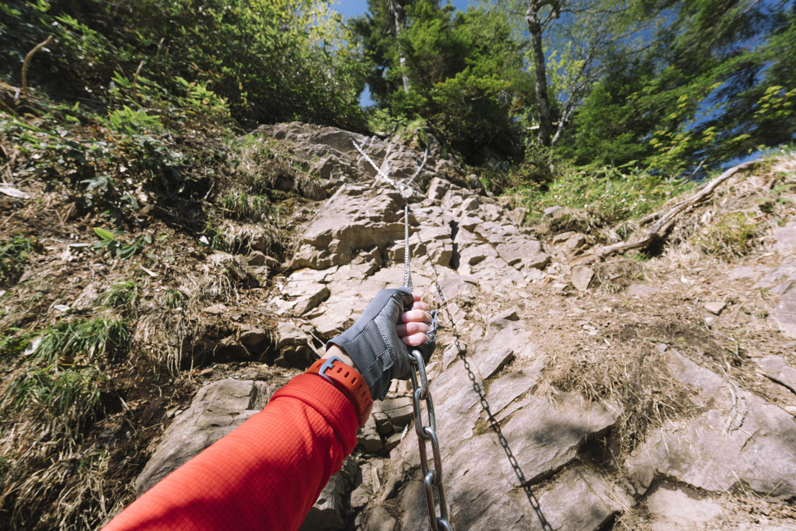 上州武尊山の行者返しで鎖を握りながら岩場を登る赤いウェアの登山者